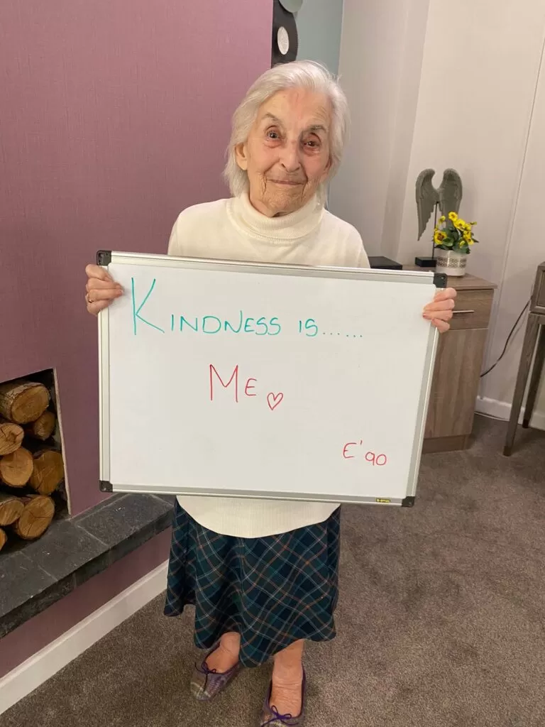 Lady holding a white board that says "Kindness is Me"